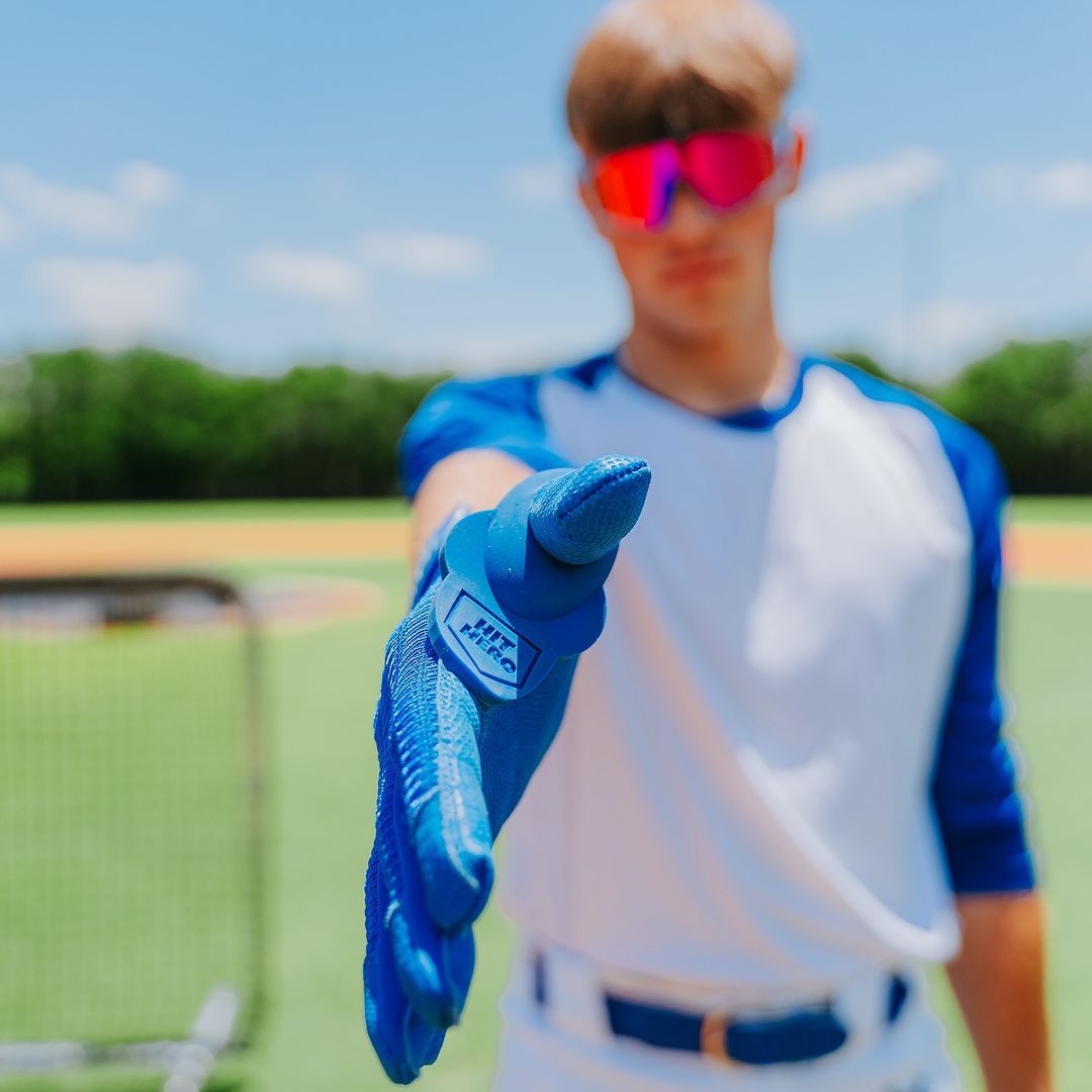 A baseball player confidently extends their hand, showcasing the Hit Hero Baseball Thumb Guard in action. The moldable design ensures a perfect fit, providing comfort and protection during every swing on the field.