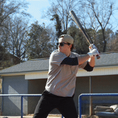 A hitter mid swing on the field wearing a Hit Hero