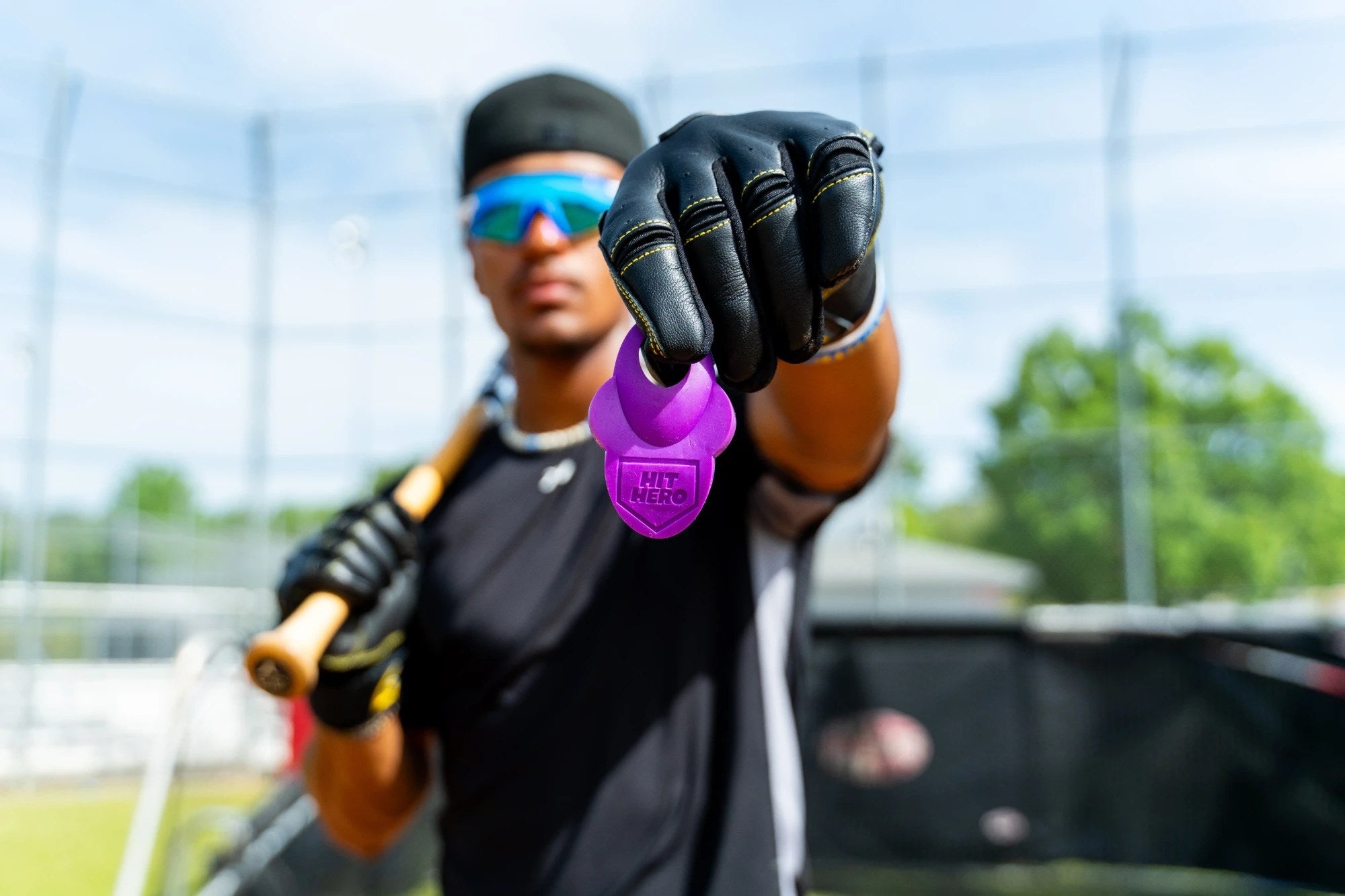 Baseball player holding out a purple Hit Hero thumb guard