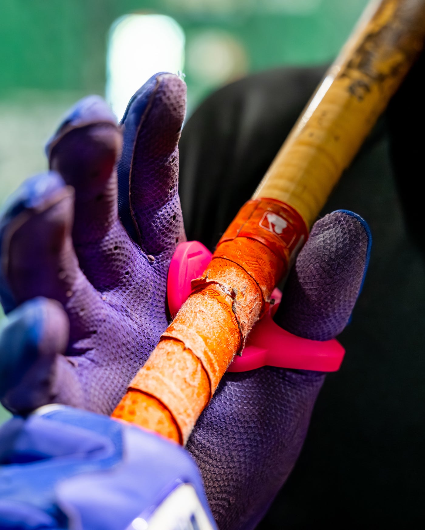 An orange Hit Hero worn on the thumb, gripping a bat